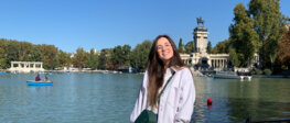 Die Studentin vor einem See, der in einem Park Madrids gelegen ist, mit Booten im Hintergrund