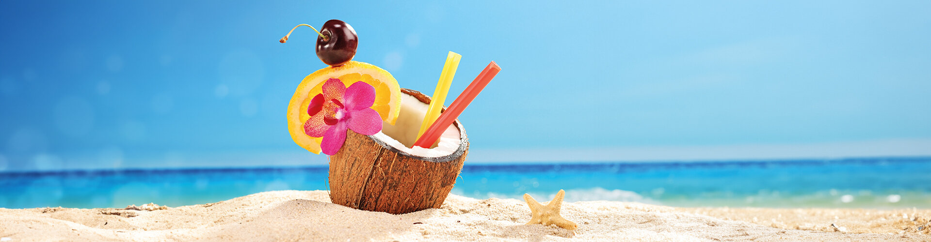 Bild: Cocktail in einer Kokosnuss, Sandstrand und Meer im Hintergrund